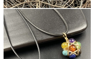 Detailed macro of handmade wire wrapped seven chakra stone pendant with golden wire work