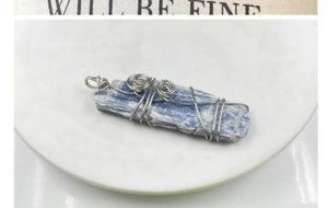 Vue macro d'un pendentif en cyanite bleue brute avec fil d'argent sur une assiette blanche