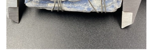 Mesure de la largeur d'un pendentif en cyanite bleue entouré de fil métallique au pied à coulisse