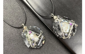 Détail du pendentif artisanal en nacre et pierres avec fil d'argent et cordon noir