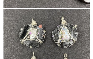 Détail de pendentifs en fil de fer et perles faits main sur socle en pierre noire