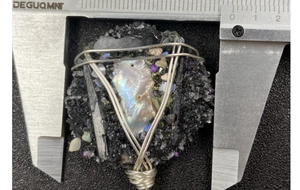 Vue détaillée d'un pendentif en perle enveloppé de fil métallique mesuré au pied à coulisse