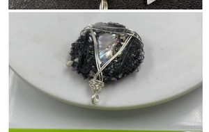 Vue détaillée d'un pendentif fait main en fil d'argent avec minéral noir et nacre
