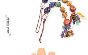 Detail of handmade woven seven chakra natural crystal stones pendant with tassel accents