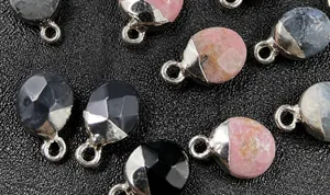 Detalle de colgantes ovalados de piedras semipreciosas facetadas con bordes bañados en oro