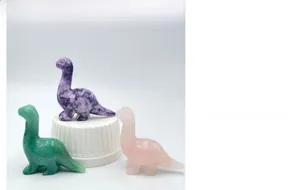 Detail of hand-carved crystal dinosaurs in green, purple, and pink natural stones