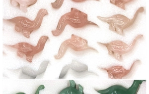 Bulk crystal dinosaur carvings in pink quartz and green jadeite foam packaging