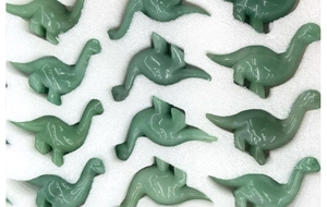 Detailed top view of bulk green gemstone dinosaur figurines in protective foam packaging