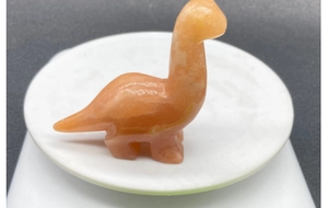 Macro detail of hand-carved orange calcite dinosaur gemstone statue with smooth finish