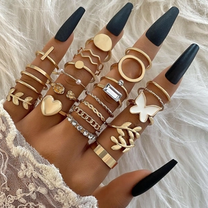 15-piece gold ring set featuring heart, butterfly, and pearl motifs on white fur background