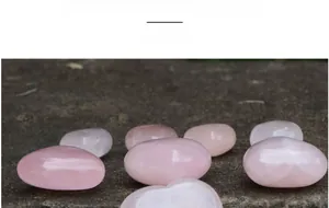 Pietre a cuore in quarzo rosa naturale lucido disposte su una superficie in pietra grigia