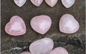 Primo piano di cristalli di quarzo rosa a forma di cuore su una superficie di roccia