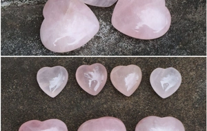 Primo piano di pietre di quarzo rosa a forma di cuore lucidate su superficie di pietra