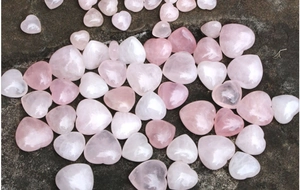 Vista dettagliata di cristalli di quarzo rosa lucidati a forma di cuore su pietra scura