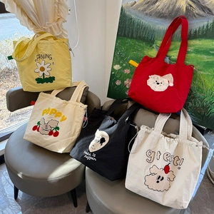 Detalle de bolsos tote de lona coloridos con bordados de felpa y cierre de cordón