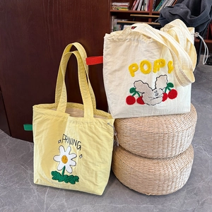 Detalle de bordados de flores y conejos en bolsos de lona con cierre de cordón