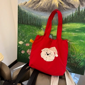 Detalle del bolso tote rojo con bordado de perro y gorro navideño floral festivo