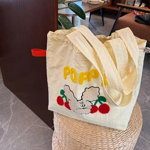 Detalle de bordado de toalla con letras Poppy y conejo en bolso tote de lona