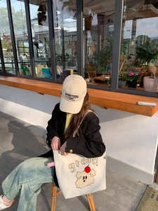 Foto lifestyle de un bolso tote de lona con estampado de perro y gorra bordada