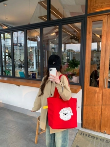 Detalle del bolso tote de lona roja con bordado de toalla de un perrito blanco