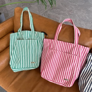 Grande borsa tote in tela a righe verticali verdi e rosa su divano in pelle