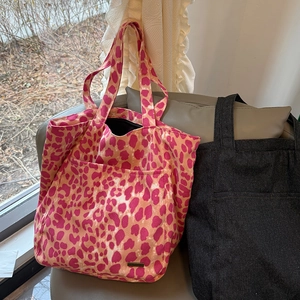 Dettaglio di borse tote in tela leopardata e nera con ampie tasche portaoggetti frontali