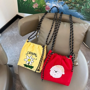 Detalle de bolsos de cubo con cordón bordados en amarillo y rojo con correas tejidas