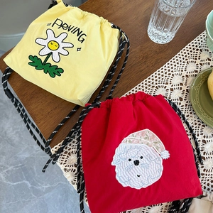 Detalle de patrones bordados de margaritas y cachorros en bolsos bandolera de nailon con cordón