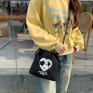 Detalle de bolso bandolera de nailon negro con bordado de perro corazón y cordón