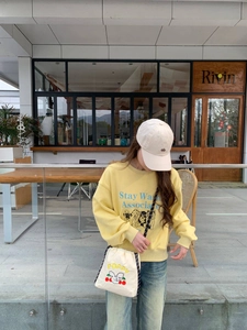 Look exterior con sudadera amarilla de perros y bolso bandolera blanco con cordón