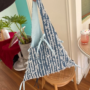 Detail der Denim-Tasche mit ausgefransten Streifen und Kordelzugverschluss