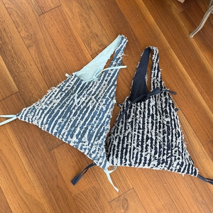 Detail der Fransenstruktur an gestreiften Jeans-Tragetaschen in Hellblau und Marineblau