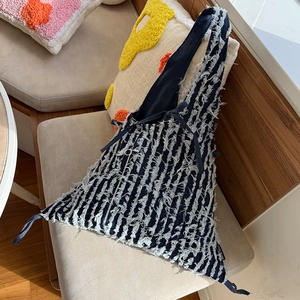 Detail einer blau gestreiften Denim-Tasche mit Fransen-Textur und Silberreißverschluss