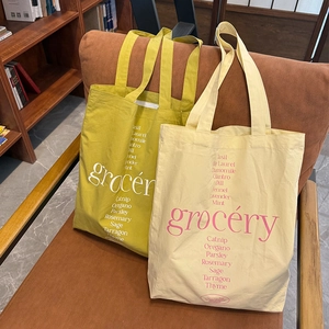 Détail de sacs fourre-tout en toile minimalistes avec imprimé d'herbes sur fauteuil