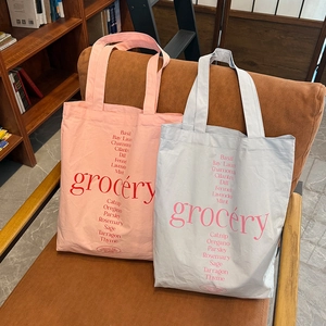 Détail de sacs fourre-tout en toile rose et grise avec imprimés d'herbes sur un banc