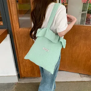 Green pleated tote bag with bubble texture fabric worn on a shoulder in street style