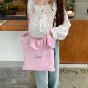 Detailed view of pink pleated tote bag with stylish ruffles and fashion text label