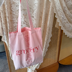 Détail du cabas en toile rose avec imprimé grocery rouge et noms de plantes aromatiques