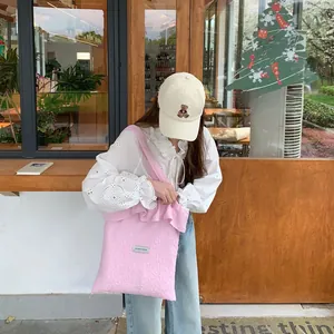 Detail of pink fleece tote bag with letter tag and cream bear embroidered baseball cap