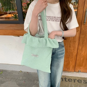 Detail of mint green ruffled tote bag with textured seersucker fabric and fashion label