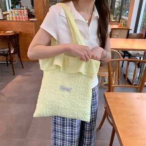Detail of light yellow textured bubble tote bag with ruffle trim and fashion label