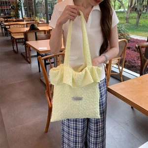 Detail of light yellow textured ruffle tote bag with YOU ARE SO FASHION label and thin straps