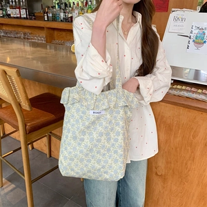 Detail of floral canvas tote bag with ruffle trim and Bisket label in a cafe setting