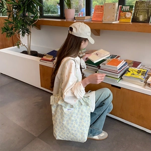 Detail of light blue floral tote bag with BISKET label in a cozy bookstore setting