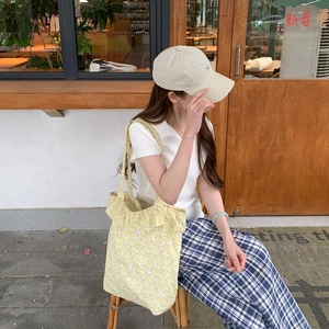 Outdoor lifestyle shot of a yellow floral canvas tote bag and a beige baseball cap