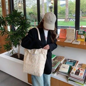 Detail of floral canvas tote bag with BISKET label shown in a casual lifestyle setting