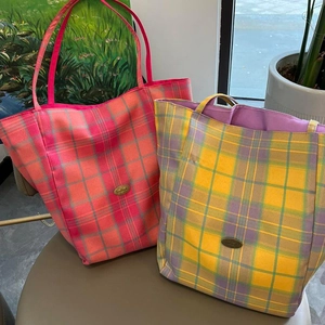Detail of plaid canvas tote bags with metal logos and spacious inner lining