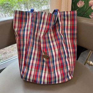 Detail of red and blue tartan canvas tote bag showing the texture and oval logo patch