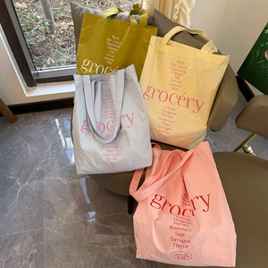 Sacs cabas grocery en toile en jaune, beige, bleu et rose posés sur une chaise