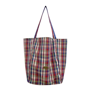 Colorful plaid canvas tote bag with long blue shoulder straps and gold metal logo